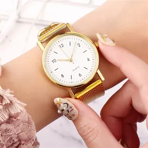 Detailansicht der eleganten goldenen Quarzuhr mit Netzarmband an einem Damenhandgelenk