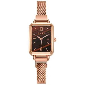 Detailed close-up of rose gold rectangular watch with brown wood texture dial and mesh strap