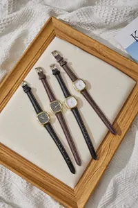 Dettaglio di orologi al quarzo quadrati dorati con cinturini in pelle neri e marroni