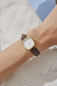 Dettaglio dell'orologio al quarzo retrò con cassa dorata e cinturino in pelle marrone
