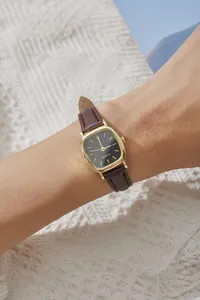 Primo piano dell'orologio al quarzo dorato con quadrante nero e cinturino in pelle marrone