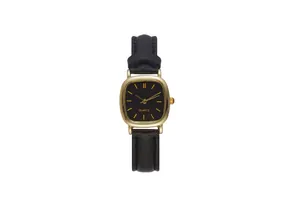 Dettaglio di un orologio vintage con cassa dorata, cinturino in pelle nera e movimento al quarzo