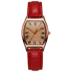 Detail of rose gold tonneau watch with red crocodile leather strap and Roman numerals