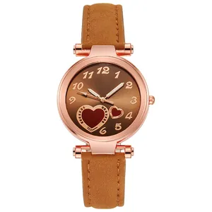 Detail of rose gold watch with brown suede strap and heart patterned brown dial