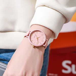 Close-up of pink leather watch with gold Arabic numerals on a minimalist dial