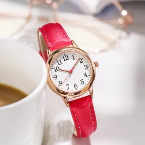 Orologio al quarzo da donna minimalista con cassa oro rosa e cinturino in pelle rossa vicino al caffè