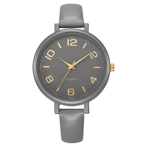 Detail shot of the gray quartz watch face with gold Arabic numerals and leather strap