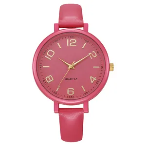 Close-up of rose red leather watch strap and gold quartz dial with classic numerals
