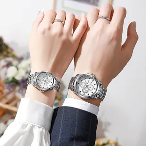 Primer plano de una pareja usando relojes de acero plateado con esfera blanca y dial
