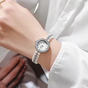 Close-up of elegant women's watch featuring a pearl chain strap and crystal bezel