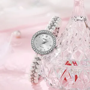 Elegant ladies quartz watch with double-row pearl strap and crystal bezel on pink background