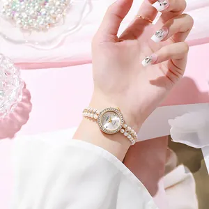 Detail of luxury women watch featuring gold case and double-row pearl bracelet band