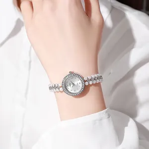 Close-up of elegant women's watch featuring pearl bead strap and crystal-encrusted bezel