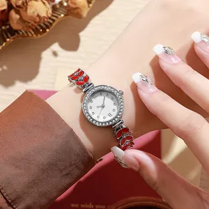 Détail de montre argentée pour femme avec lunette en strass et maillons émaillés rouges
