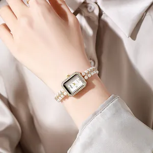 Detail of elegant pearl chain watch with rectangle rhinestone bezel on woman's wrist
