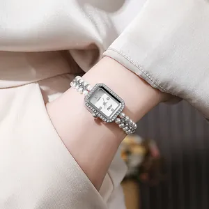 Close-up of rectangular silver watch with crystal bezel and double pearl chain strap