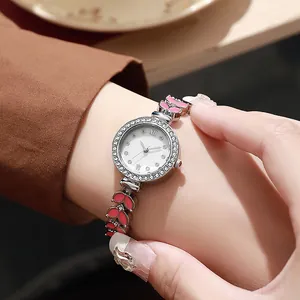Détail d'une montre bijou pour femme avec lunette en strass et breloques rose sirène
