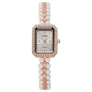 Detailed macro view of rectangle gold watch face with pearl bracelet and inlaid crystals