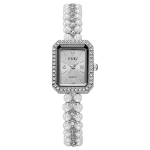 Close-up of rectangular quartz watch with pearl strap and diamond-encrusted silver bezel