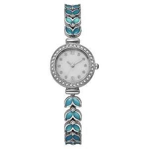 Détail d'une montre femme argentée avec maillons feuilles, émail bleu et strass brillants