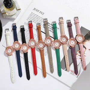 Flat lay of quartz watch set in ten colors featuring diamond-encrusted bezels on marble