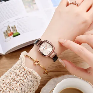 Close-up of rose gold square quartz watch with crystal bezel and black leather strap
