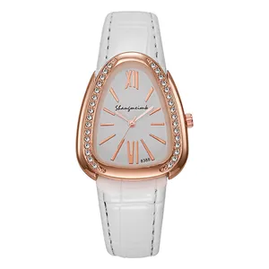 Détail du boîtier montre bouclier or rose avec cristaux et bracelet en cuir blanc