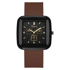 Detail view of square black dial with golden markers and brown silicone strap