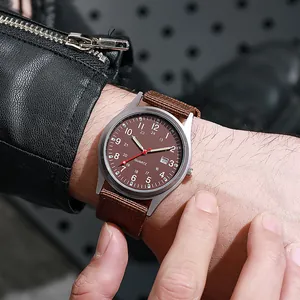 Detail of military style quartz watch with brown canvas strap and date window on wrist