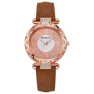 Detailed close-up of rose gold watch dial with rhinestones and brown suede leather strap