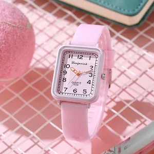 Pink rectangular quartz watch with silicone strap displayed on a grid decorative background