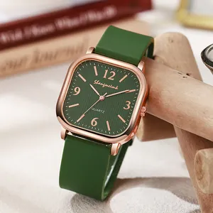Retro square women's quartz watch with dark green dial and silicone strap on wooden base