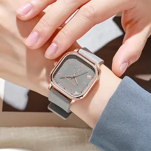 Détail d'une montre carrée en or rose avec bracelet en silicone gris et chiffres romains