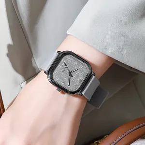Detailed view of square quartz watch with grey silicone strap and textured dial on wrist