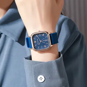 Détail d'une montre carrée or rose avec cadran bleu et bracelet silicone texturé au poignet