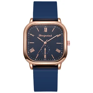 Détail d'une montre carrée or rose avec cadran romain bleu marine et bracelet silicone