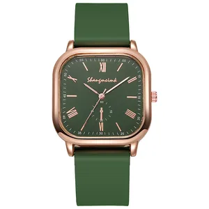 Détail d'une montre carrée or rose avec bracelet silicone vert et chiffres romains