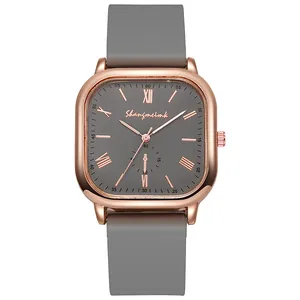 Détail de montre carrée en or rose avec chiffres romains et bracelet en silicone