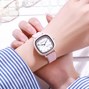 Pink minimalist square quartz watch with leather strap worn on wrist in a bright office setting