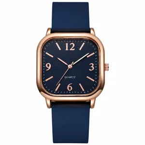 Square quartz watch with rose gold case and navy blue leather strap on white background