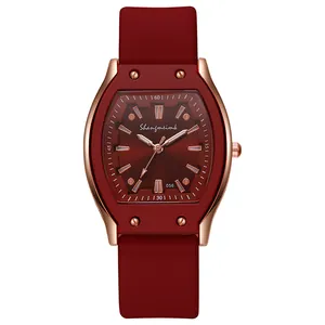 Detailed close-up of wine red silicone strap and rose gold tonneau quartz watch case