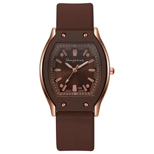 Detail of rose gold tonneau case watch with chocolate brown silicone strap and dial