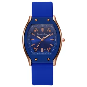 Detailed close-up of a tonneau-shaped rose gold watch with a navy blue silicone strap