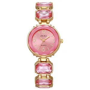 Détail d'une montre à quartz dorée avec bracelet en cristal rose et cadran à texture solaire