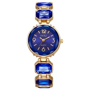 Détail de montre quartz dorée avec accents en cristal bleu et cadran soleil