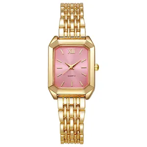 Dettaglio macro di un orologio rettangolare dorato con quadrante rosa e numeri romani
