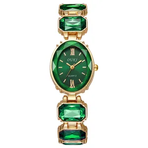 Vue macro d'une montre à quartz dorée avec cristaux vert émeraude et bracelet doré