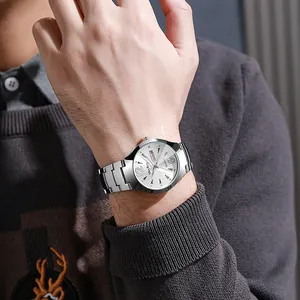 Primer plano de un reloj de cuarzo para hombre con correa de acero plateada y fecha en la muñeca