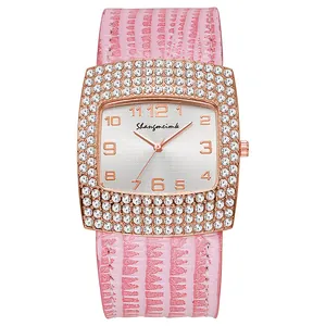 Detail of rose gold square watch dial with rhinestones and pink crocodile leather strap