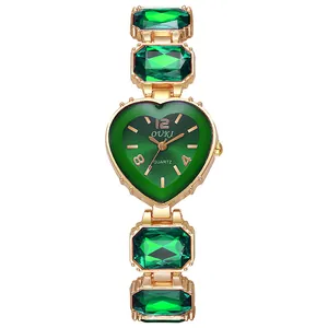 Dettaglio dell'orologio al quarzo a cuore con pietre verdi e cinturino in metallo dorato